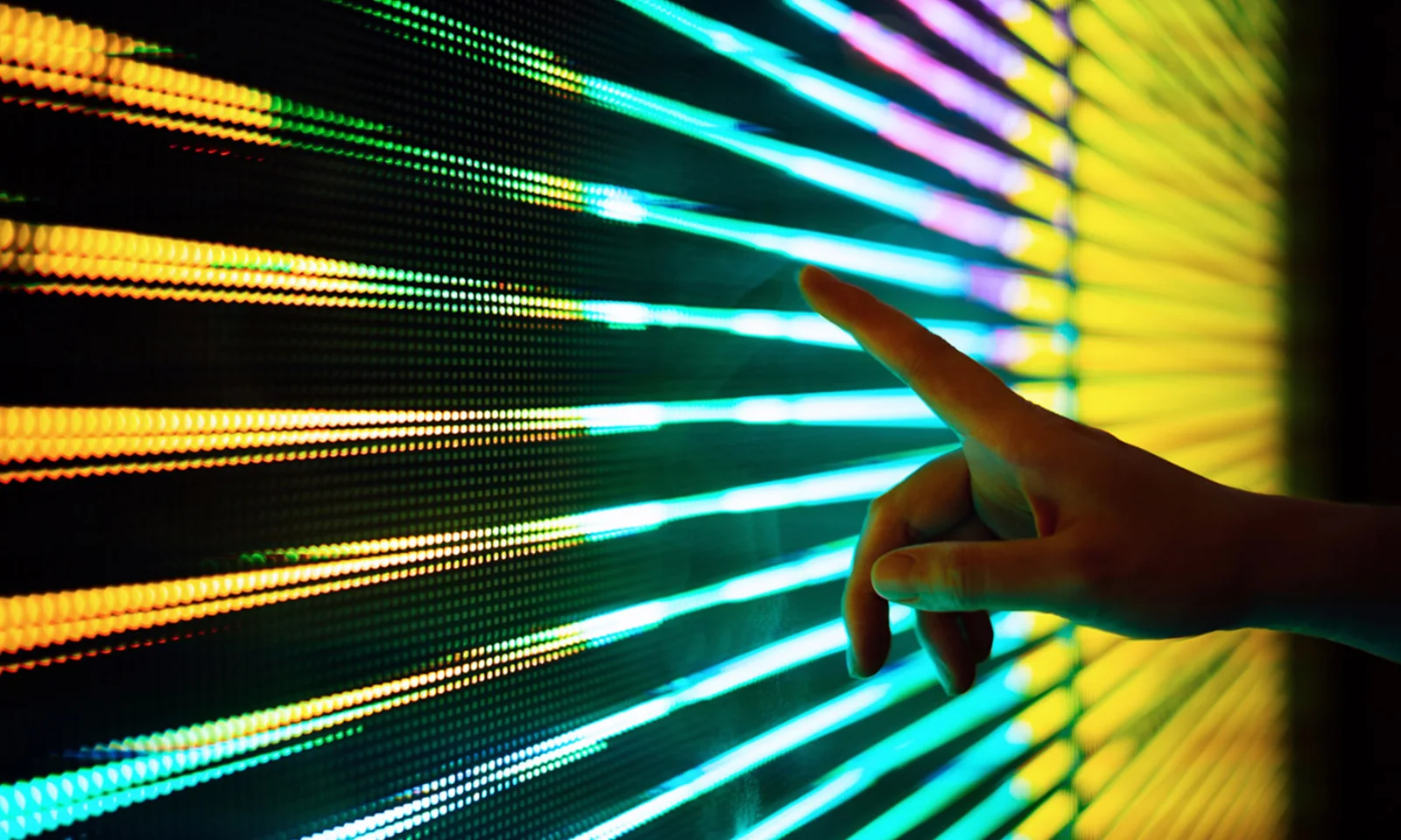 A hand interacting with a vibrant LED digital interface, showcasing dynamic data or light patterns.