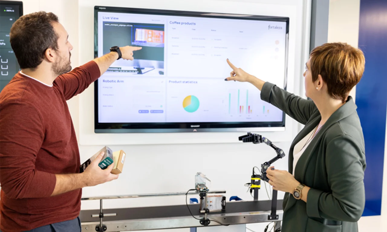 Two professionals interacting with a digital display in an innovation lab, focusing on industry automation and analytics.